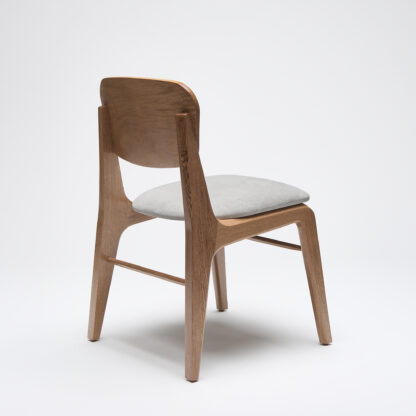 silla moderna de madera sin descansabrazos con asiento tapizado en tela color gris vista desde atrás