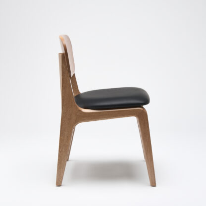 silla minimalista de madera sin descansabrazos con asiento tapizado en piel color negro vista lateral