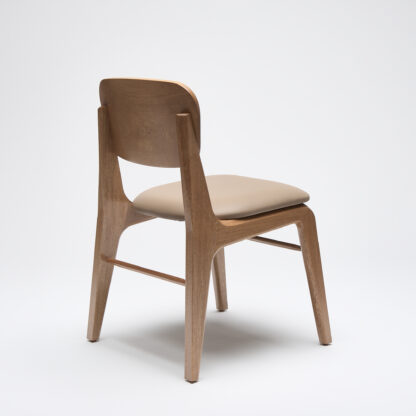 silla minimalista de madera sin descansabrazos con asiento tapizado en piel color taupe vista desde atrás